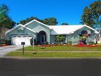 Well-maintained home with lush green lawn, colorful flowerbeds, and a charming two-car garage at 13625 Deventer Ct, Hudson, FL 34667