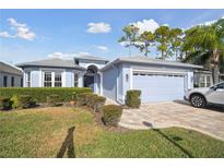 Light blue house with two-car garage and well-manicured lawn at 11644 Spindrift Loop, Hudson, FL 34667