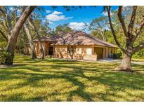 Charming single-Gathering home with a brown roof, brick accents, and a lush green lawn at 7443 Oak Tree Ln, Spring Hill, FL 34607