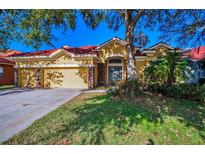 Charming single-story home with red tile roof, yellow stucco, stone accents, and a well-maintained lawn at 11645 Belle Haven Dr, New Port Richey, FL 34654