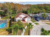 Elevated view of home with pool, two-car garage, and fenced backyard at 7717 Foxbear Ct, New Port Richey, FL 34655