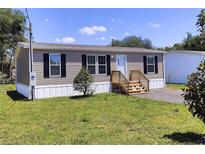 Single-wide manufactured home with a landscaped yard and wooden steps at 16076 Narrow St, Spring Hill, FL 34604