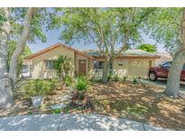 Tan house with brown roof, landscaping, and driveway at 3049 Moog Rd, Holiday, FL 34691