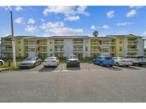 Front view of a yellow condo building with ample parking at 455 Alt 19 S # 163, Palm Harbor, FL 34683