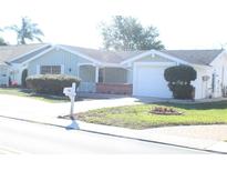 House exterior featuring light teal siding, brick accents, and a two-car garage at 3518 Moog Rd, Holiday, FL 34691