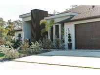 Modern home exterior with clean lines, wood accents, and manicured landscaping with decorative plant life at 12149 Chapman Ave, Port Charlotte, FL 33953