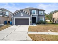 Two-story home features a gray exterior, attached garage, and well-manicured front lawn at 14143 Wake Robin Dr, Brooksville, FL 34604