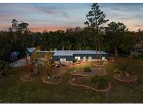 Expansive ranch-style home at dusk features mature trees and meticulously landscaped front yard with garden beds at 7815 Tanglewood Dr, New Port Richey, FL 34654