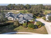 Stunning single-story home featuring mature landscaping, a paved driveway, and views of the lush green golf course at 2595 Royal Liverpool Dr, Tarpon Springs, FL 34688