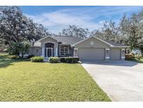 Charming one story home with a well manicured green lawn and a three car garage at 12910 Oak Nut St, Hudson, FL 34667