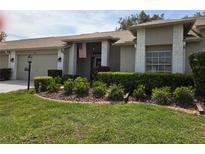 Charming single-story home featuring a well-manicured lawn, an American flag, and a neatly landscaped garden at 18049 Tarrington Pl, Hudson, FL 34667
