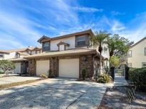 Inviting townhouse exterior showing two-car garage, brick accents, tile roof, and well-maintained landscaping at 1203 Clays Trl # 406, Oldsmar, FL 34677