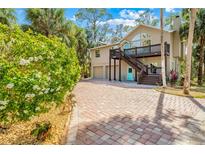 Inviting two-story home featuring a private balcony, brick driveway and lush landscaping at 8711 Betty St, Port Richey, FL 34668