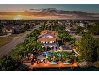 Stunning waterfront home featuring a private dock, pool, and lush tropical landscaping at sunset at 3308 Oleander Dr, Hernando Beach, FL 34607