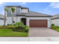 Inviting two-story home showcasing a well-manicured lawn and a brick paved driveway to the two-car garage at 17026 Shell Bay Dr, Land O Lakes, FL 34638