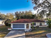 Charming single-story home with a red-tiled roof, a screened garage, and neutral-colored exterior paint at 5518 Pinehurst Dr, Spring Hill, FL 34606