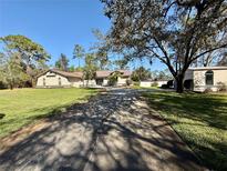 Sprawling single-story home featuring a large driveway and well-manicured lawn at 7090 Red Oak Loop, New Port Richey, FL 34654