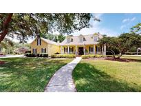 Charming yellow home with a welcoming front porch and well-manicured lawn and walkway at 1031 Pomme De Pin Ln, New Port Richey, FL 34655