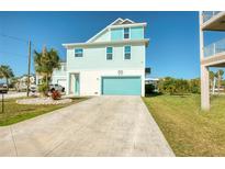 Inviting coastal home with a turquoise garage door and a spacious stamped concrete driveway at 6613 Josie Ln, Hudson, FL 34667
