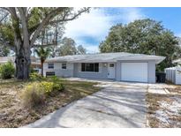 Charming single story home featuring mature trees, a front yard, and a one car garage at 686 Manor W Dr, Dunedin, FL 34698