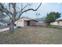 Single-story house featuring a brick facade, front porch seating area, and an attached single car garage at 8715 Robilina Rd, Port Richey, FL 34668