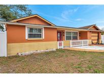 Charming single-story home featuring a white picket fence and colorful orange and yellow exterior at 9220 Saint Regis Ln, Port Richey, FL 34668