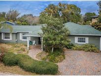 Charming single-story home featuring a well-manicured lawn, mature trees, and a brick-paved driveway at 646 Riverside Dr, Tarpon Springs, FL 34689