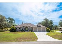 Charming exterior of the house with a well-manicured lawn and a three-car garage at 10188 Whisper Ridge Trail Trl, Weeki Wachee, FL 34613
