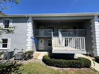 A clean, grey two-story condo building with a white railing on the porch and well-maintained landscaping at 12027 Hoosier Ct # 104, Hudson, FL 34667