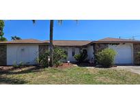 Charming single-story home featuring stone accents, lush landscaping, and a well-maintained front yard at 1414 Grand Blvd, Holiday, FL 34690