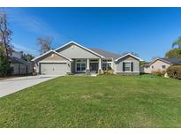 Charming home features a lush green lawn, two-car garage, and covered porch with stone accents at 5139 Jenson Ave, Spring Hill, FL 34608
