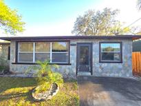 Charming single-story home featuring decorative stone work, manicured lawn, and lush landscaping at 5800 Massachusetts Ave, New Port Richey, FL 34652