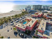 Aerial view of the property with a pool and beach access, surrounded by lush greenery and ample parking at 6800 Sunset Way # 1006, St Pete Beach, FL 33706