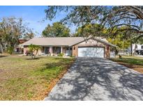 Charming single-story brick home with well-maintained lawn and mature trees for a peaceful curb appeal at 12511 Stone House Loop, Hudson, FL 34667