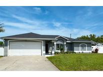 Charming single-story home boasts a well-manicured lawn, two-car garage, and sleek gray paint scheme at 5801 65Th N Ter, Pinellas Park, FL 33781