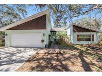 Charming home exterior with a well-maintained lawn, mature trees, and a welcoming entrance at 7065 Red Oak Loop, New Port Richey, FL 34654
