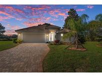Charming home featuring a brick driveway, lush lawn, and well-maintained landscaping set against a beautiful sunset sky at 8910 Jericho Rd, Weeki Wachee, FL 34613