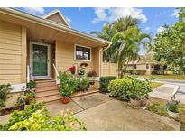 Inviting front entrance with flower pot decor and wood stairs leading to green door at 1002 Caravel Ct, Tarpon Springs, FL 34689