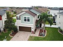 Charming two-story home with a well-manicured lawn, brick driveway and a beautiful palm tree in the front yard at 11611 Lake Blvd, New Port Richey, FL 34655