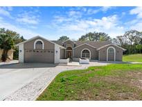 Charming single-story home with a gray exterior, white brick accents, and well-manicured front lawn at 14448 Linden Dr, Spring Hill, FL 34609