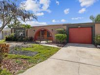 Single story home featuring stucco exterior, red garage door, archway entry, and mature landscaping at 3730 Sail Dr, New Port Richey, FL 34652