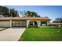 Charming single-story home with a clay tile roof and a well-manicured front lawn at 8110 Bismark Ct, Port Richey, FL 34668