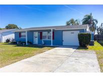Charming single-story blue home featuring a well-manicured lawn and a private driveway at 10245 Regency Park Blvd, Port Richey, FL 34668