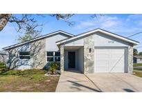 Charming home featuring a stone facade, an attached garage, and freshly manicured lawn at 13726 Michelle Ave, Hudson, FL 34667