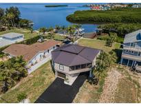 An exterior view of a unique home, including the driveway, garage, and view of the intercoastal waters behind the home at 1616 Sea Breeze Dr, Tarpon Springs, FL 34689
