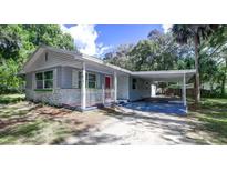 Charming single-story home features a covered carport and quaint front porch with red accents at 406 Zoller St, Brooksville, FL 34601