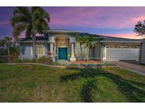 Charming single-story home featuring a beautiful teal door, well-manicured lawn, and lush landscaping at 494 Village Dr, Tarpon Springs, FL 34689