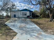 Charming single-story home with a long driveway and attached garage, surrounded by mature trees and landscaping at 7278 Lamplighter St, Spring Hill, FL 34606