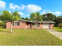 Charming red brick home with a well-manicured lawn and two palm trees in the front yard at 9512 Sunshine Blvd, New Port Richey, FL 34654