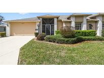 Charming single-story home featuring a well-manicured lawn and an attached two-car garage at 18129 Baywood Forest Dr, Hudson, FL 34667